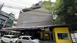 A hostel with a yellow exterior and a grey roof. There are two cars parked in front. - comfy crib hostel  (Bangkok)