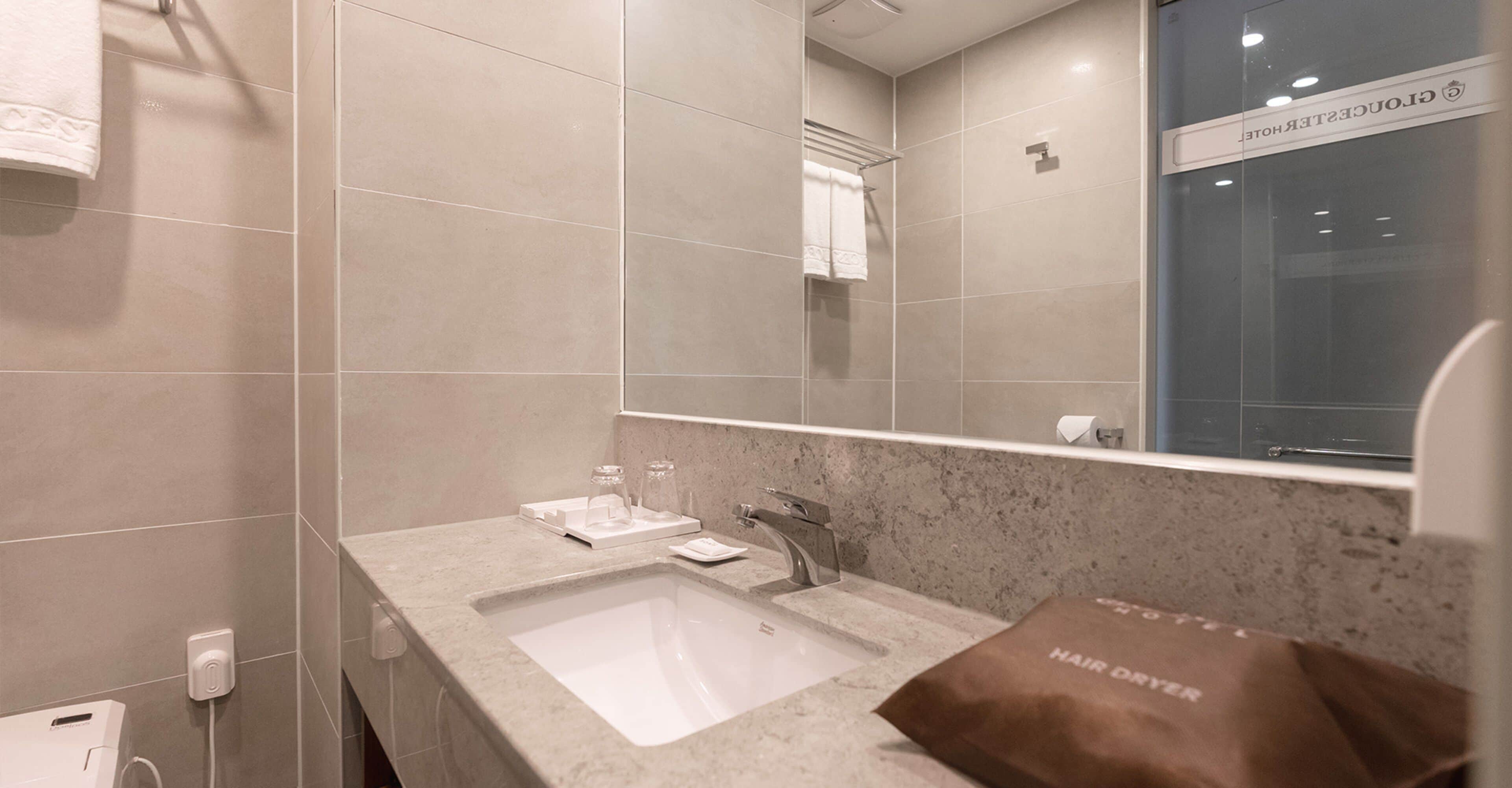 A modern bathroom with a large mirror, a sink, and a towel rack.