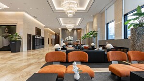 A modern hotel lobby with a reception desk, seating area, and large windows. - Gloucesterhotel Jeonju  (Jeonju)