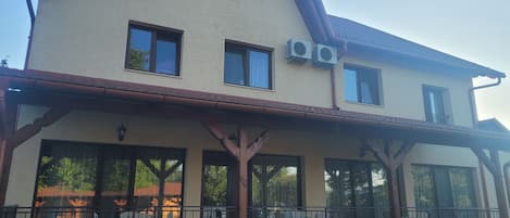 A two-story building with a balcony, large windows, and a visible sign.