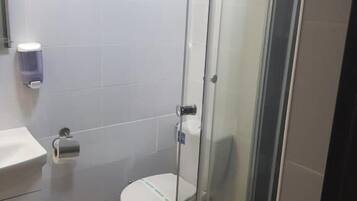 Un bagno moderno con doccia a vetro, un water e un lavandino con cestino.