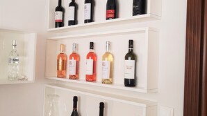 A wine rack with multiple bottles on three shelves, a remote control, and a menu on a table. - Villa Lotus (Deva)