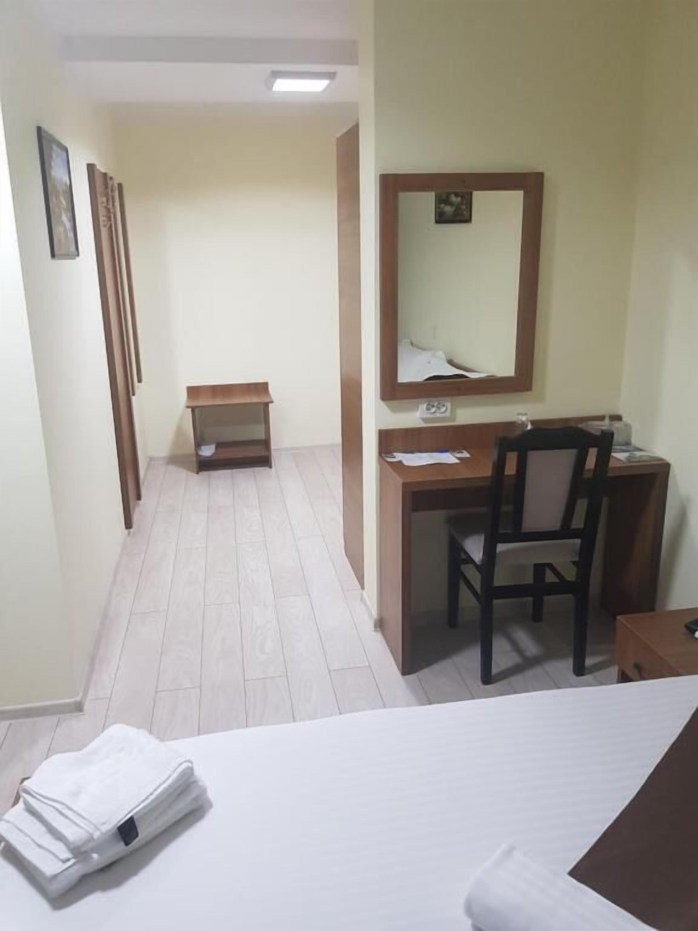 Una habitación de hotel con cama, escritorio, silla, mesita y espejo.