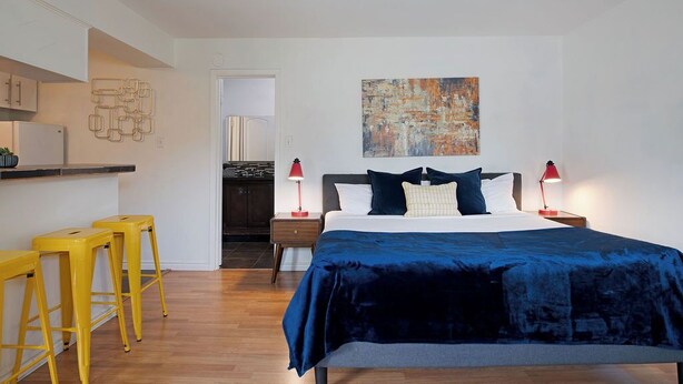 Un dormitorio moderno con una cama grande, dos mesitas de noche, una lámpara roja y un cuadro en la pared.