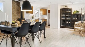 A modern kitchen with a dining area, featuring a black dining table, black chairs, and a hanging light fixture.