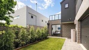 Ein modernes Wohngebäude mit gepflegtem Rasen, Holzzaun und Garage.