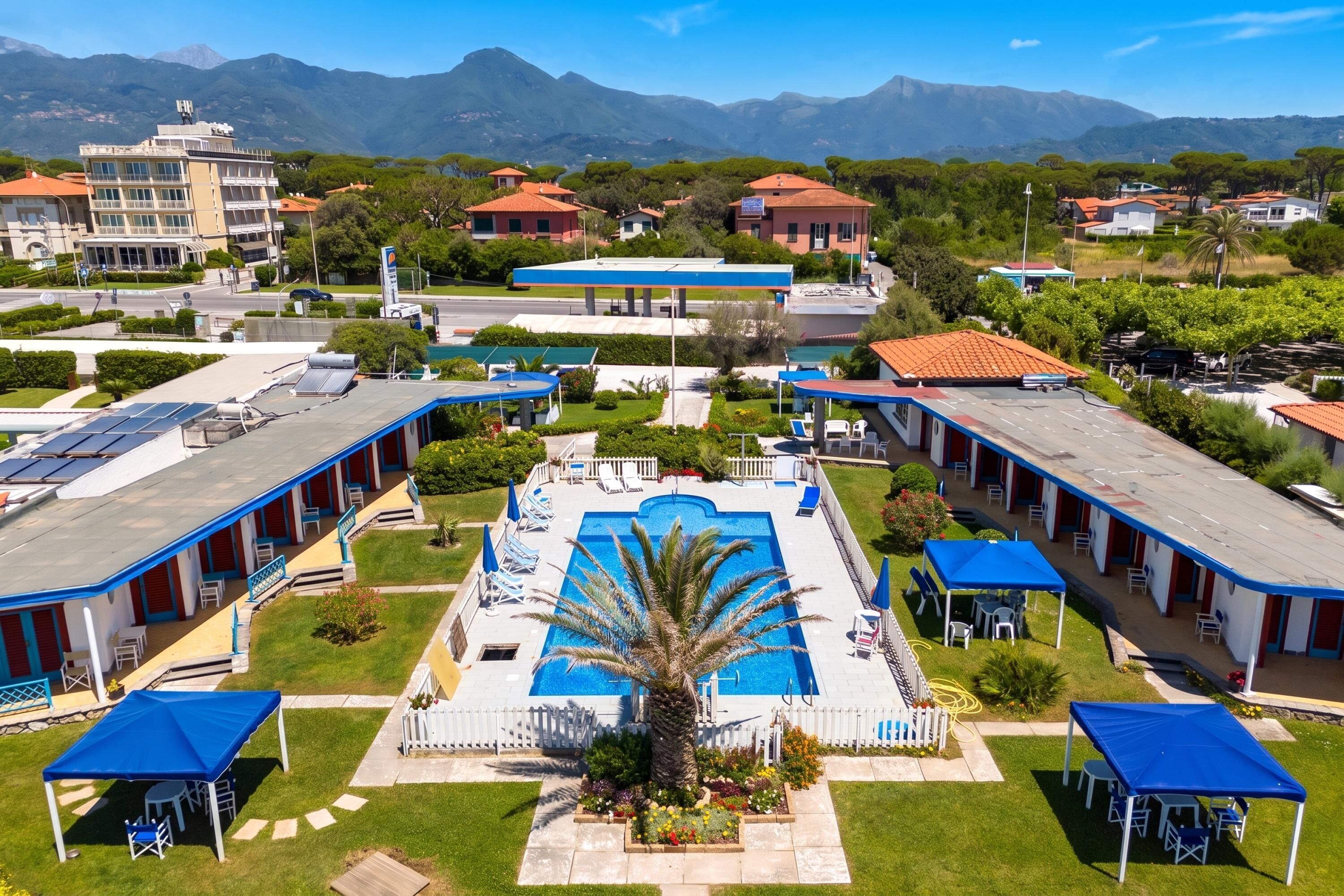 A hotel with a swimming pool, multiple rooms, and a mountainous backdrop.