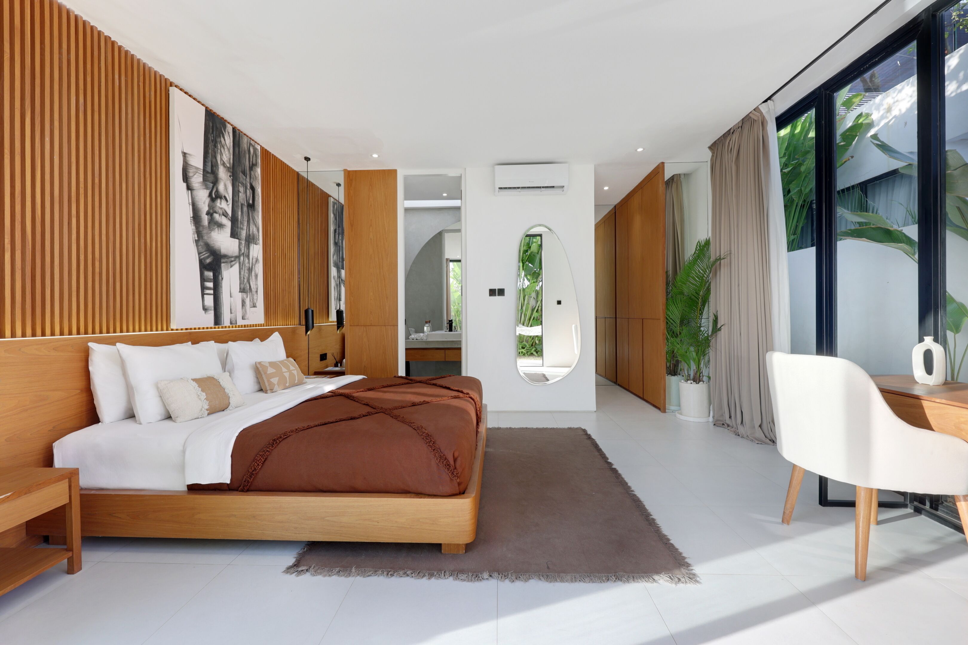 Une chambre moderne avec un grand lit, un bureau et une vue sur la verdure.
