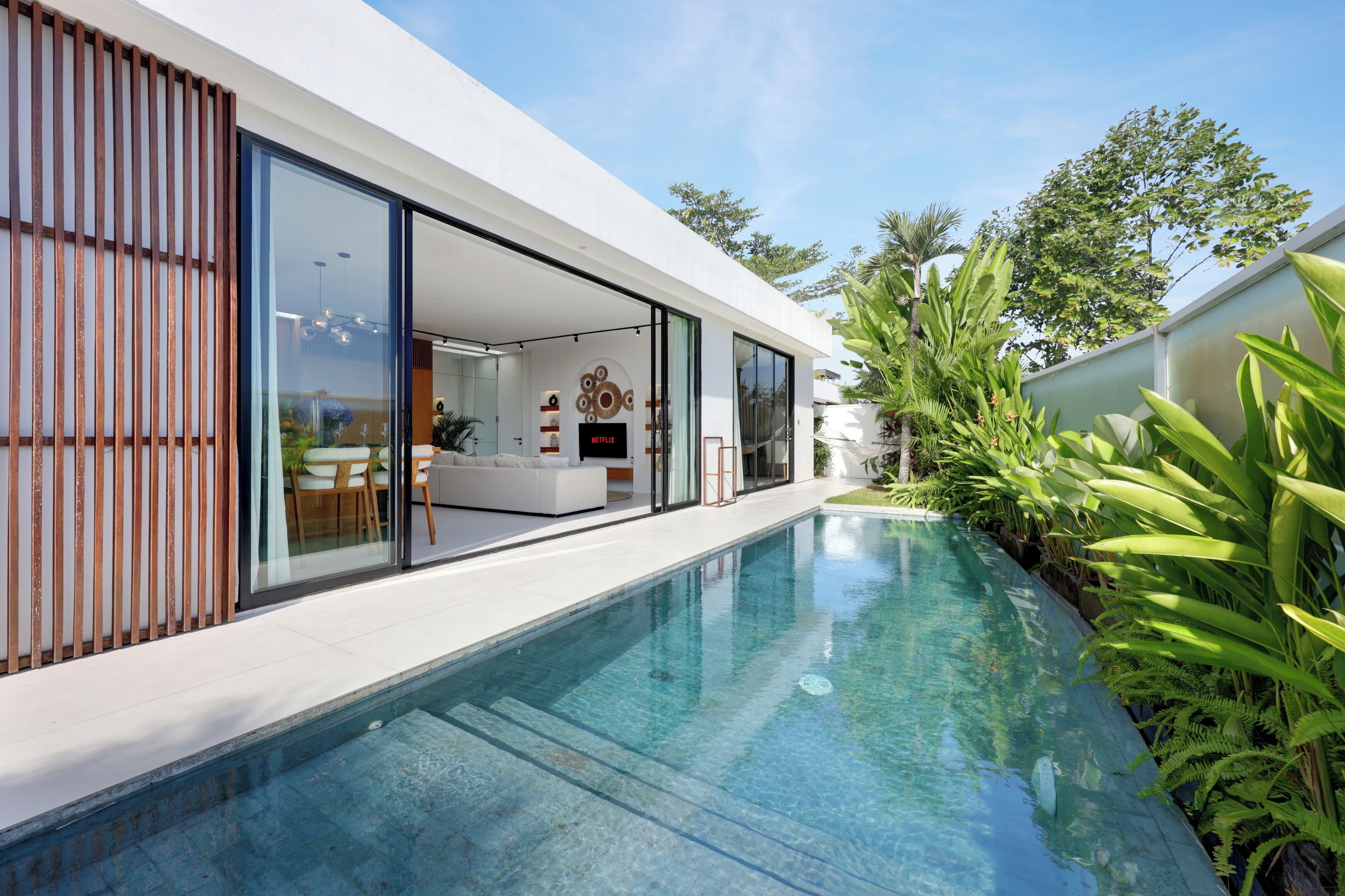 A modern house with a swimming pool, large glass doors, and a Netflix sign.