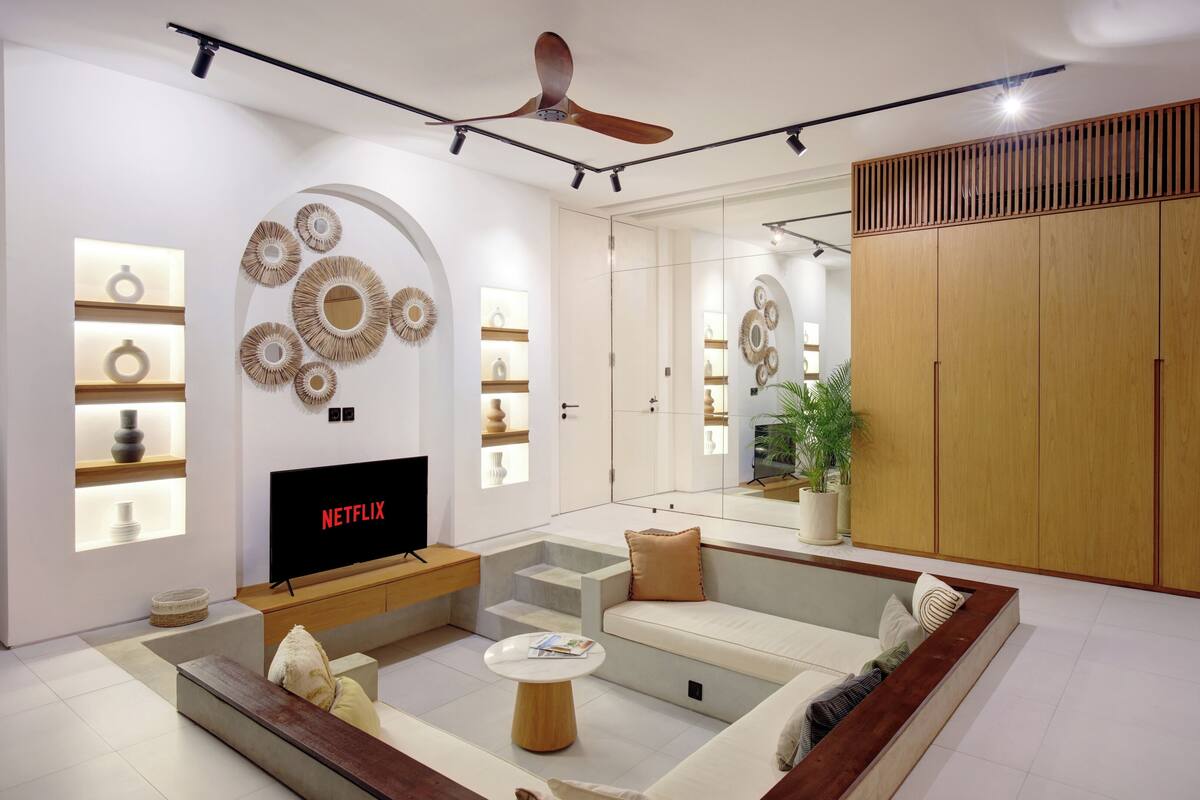 Ein modernes Wohnzimmer mit Flachbildfernseher, Deckenventilator und großem Holzschrank.