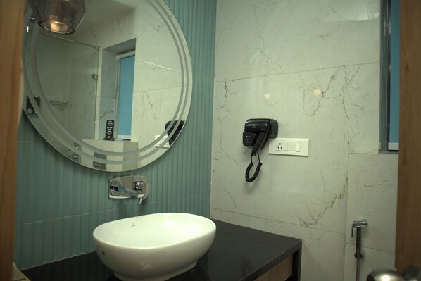 Un baño con un lavamanos blanco, un espejo redondo, un teléfono móvil y una ducha.
