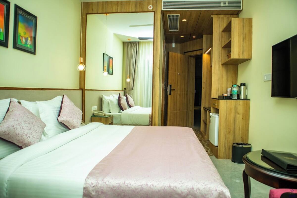 Habitación de hotel con cama, escritorio, espejo y televisor.