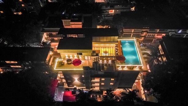 An aerial view of a modern hotel with a swimming pool, multiple balconies, and well-lit outdoor areas. - Hotel Southgate Goa (Calangute)