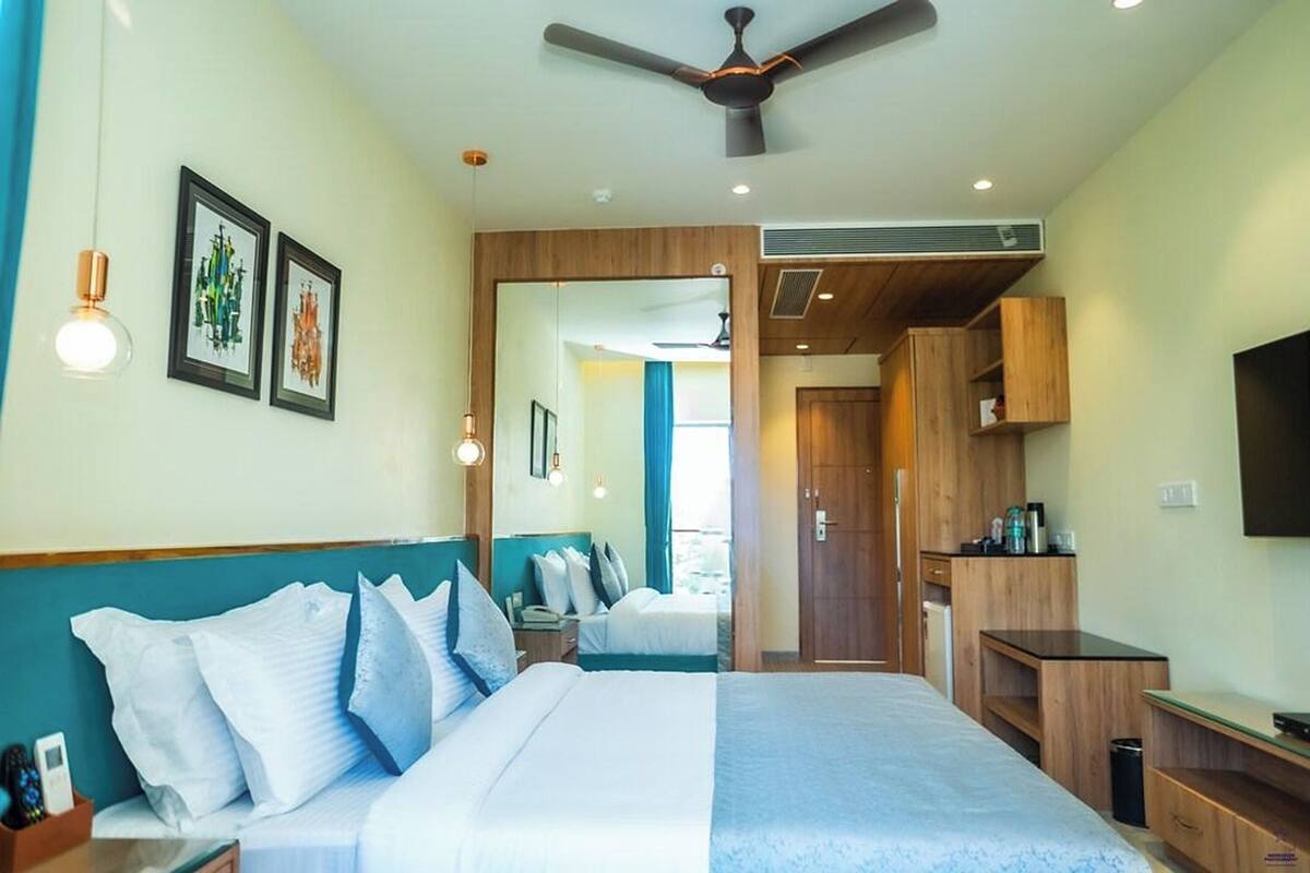 Una habitación de hotel con cama, escritorio, televisor y armario.