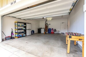 Een garage met een tafelvoetbaltafel, een schoenenrek en een boiler.