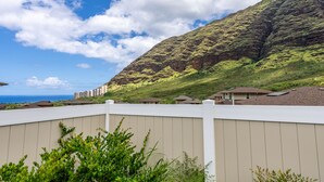 A residential area with houses, a white fence, and a mountain in the background. - Pakele Oahu by AvantStay | 5 Min to Makaha Beach (Waianae)