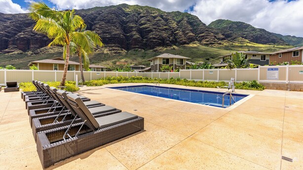 A pool area with lounge chairs, a swimming pool, and a mountain backdrop. - Pakele Oahu by AvantStay | 5 Min to Makaha Beach (Waianae)