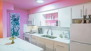 A kitchen with white cabinets, a white countertop, a sink, a stove, and a refrigerator.