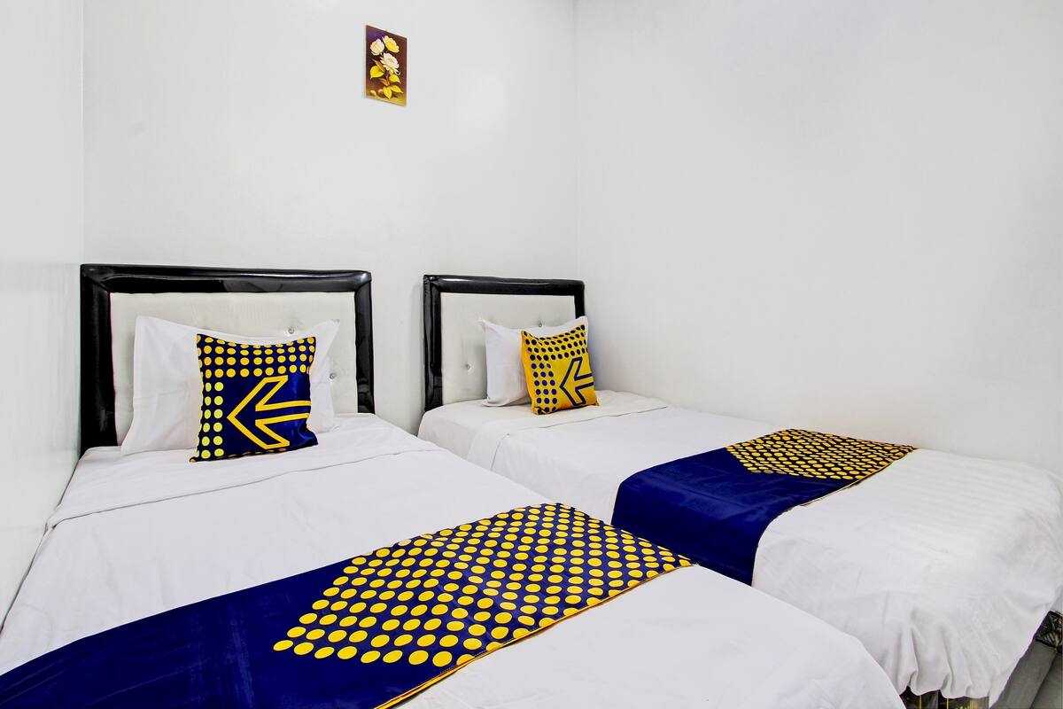Two single beds with black headboards and white bedding, each with a blue and yellow patterned bedspread.