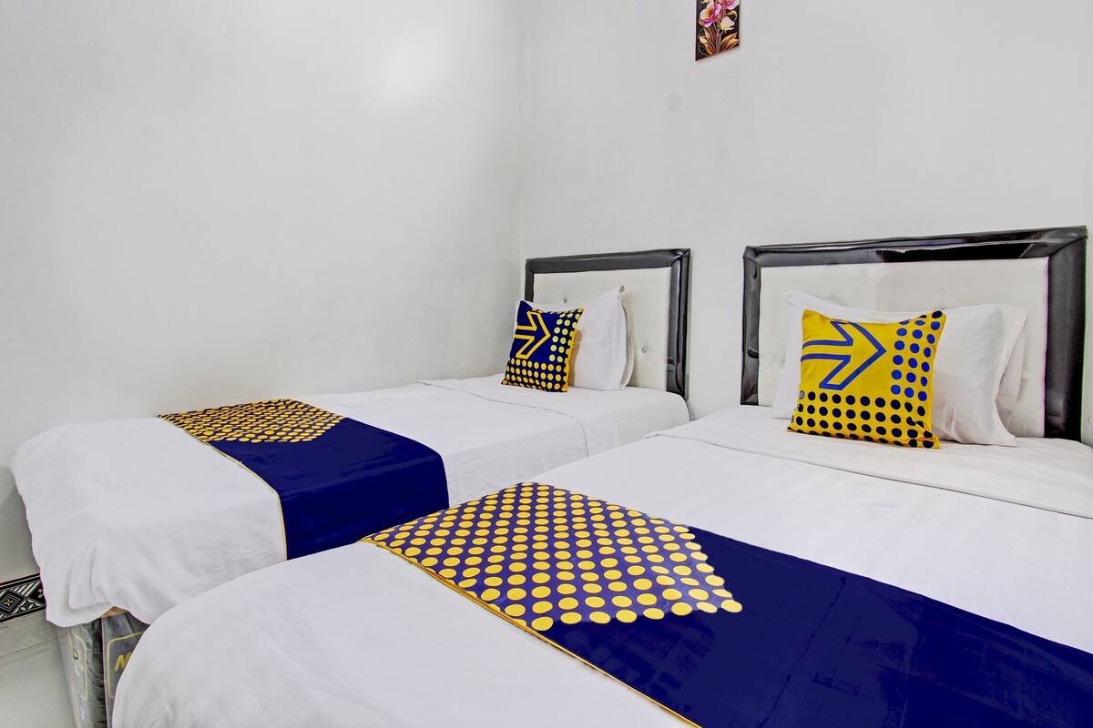 A hotel room with two beds, each with a white mattress and a blue and yellow polka dot bedspread.