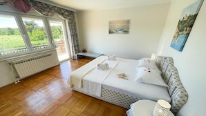 A bedroom with a bed, a bedside table, a radiator, and a window with curtains. - Apartment in Croatia near Adriatic Coast (Jadranovo)