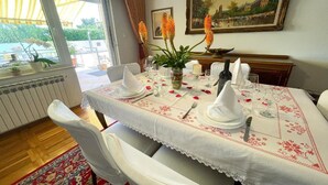 A dining room with a table set for four, white tablecloth, and a vase with flowers. - Apartment in Croatia near Adriatic Coast (Jadranovo)