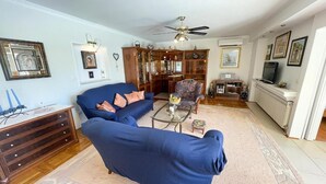 A living room with a blue sofa, a patterned armchair, a glass coffee table, and a ceiling fan. - Apartment in Croatia near Adriatic Coast (Jadranovo)