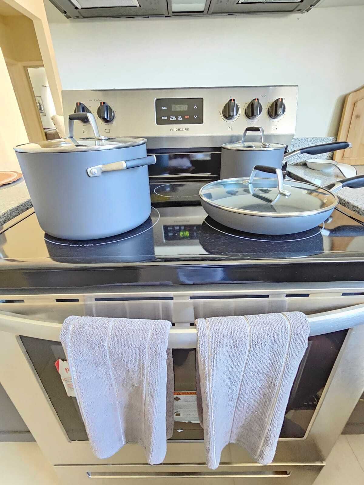 Een keuken met een fornuis, oven en twee pannen op het aanrecht.