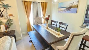 Un coin repas avec une table en bois foncé, des chaises de couleur beige et un vase rempli de fleurs.