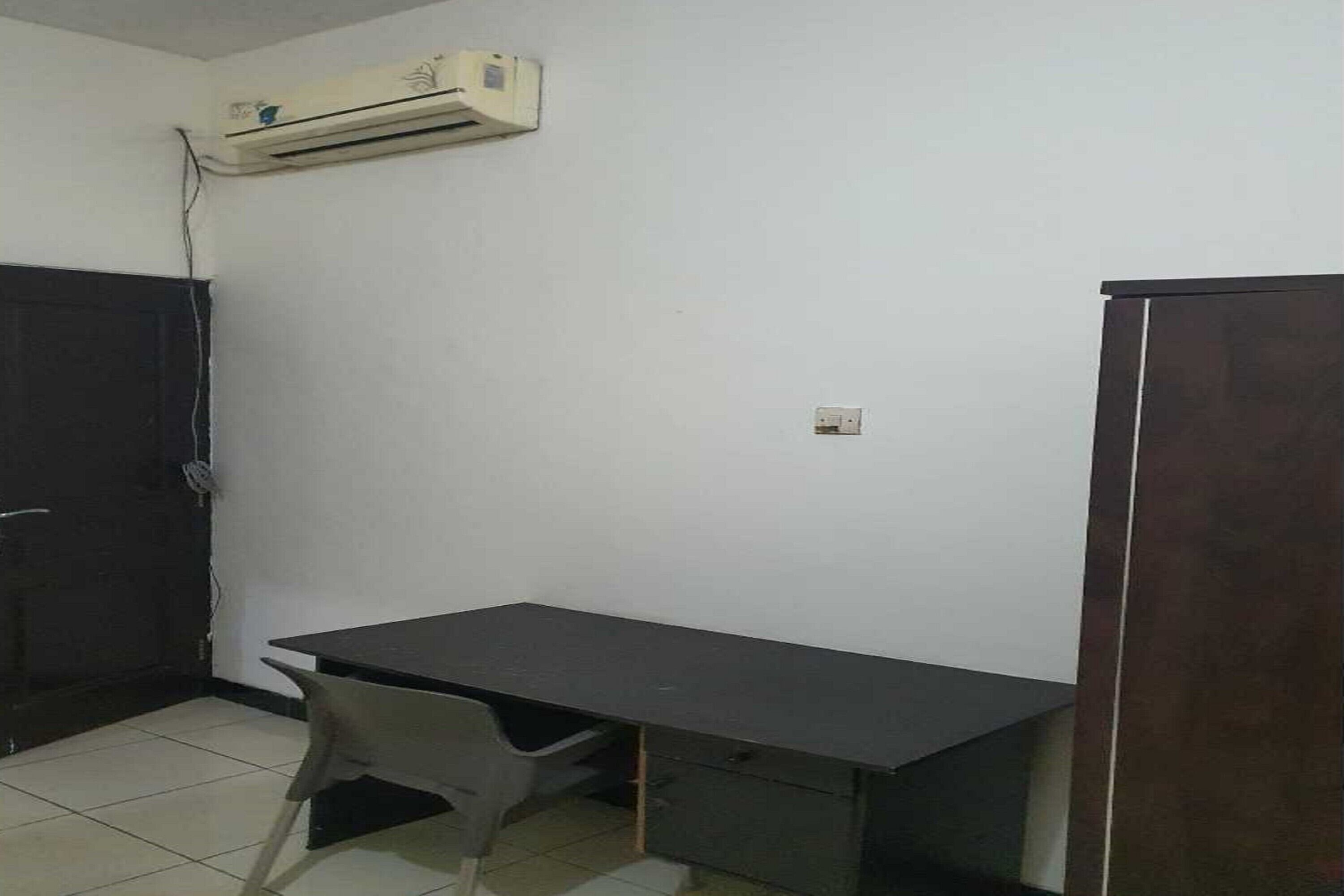 Una habitación con escritorio, silla, armario y equipo de aire acondicionado.