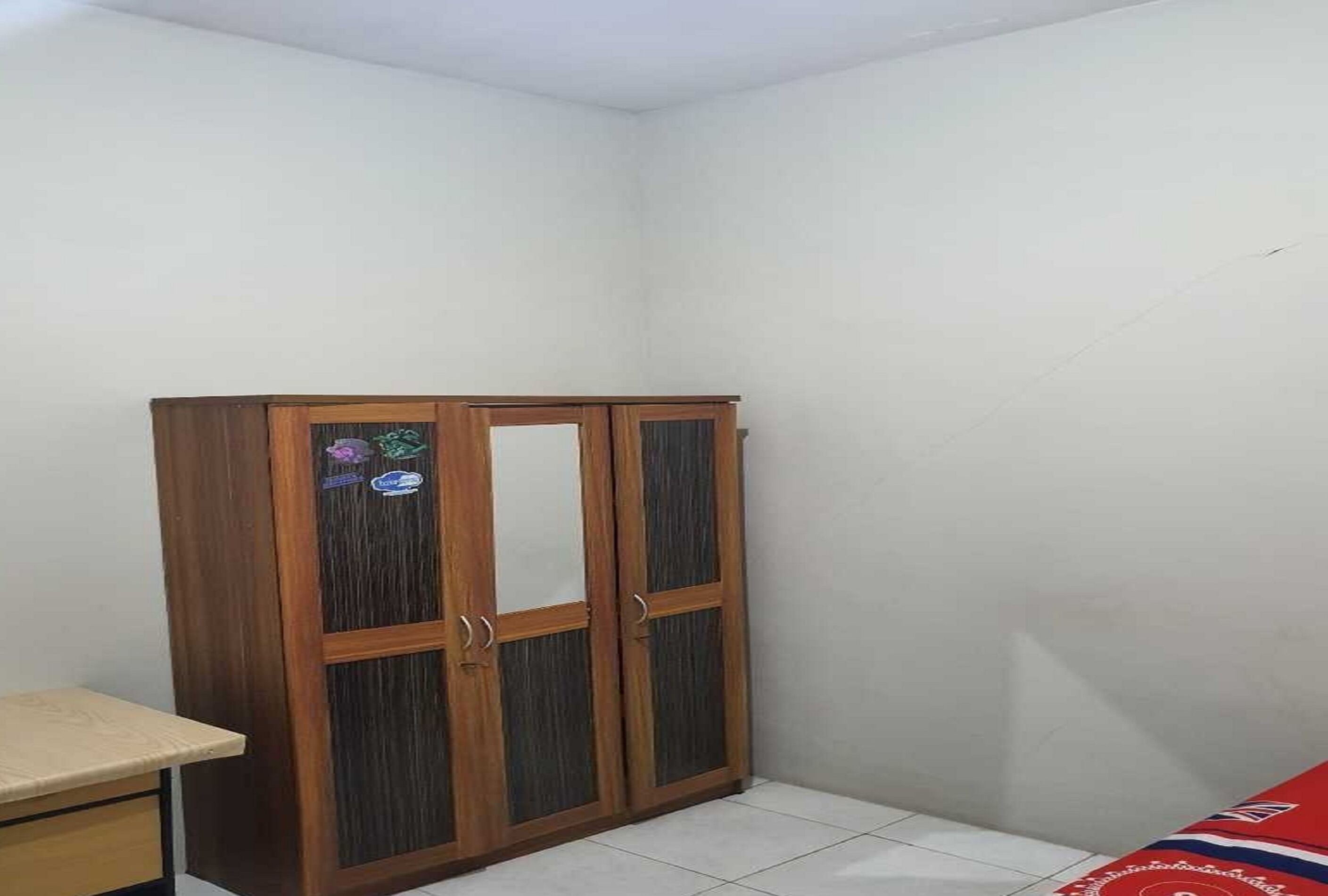 Een kamer met een houten garderobe, een klein bureau en een betegelde vloer.