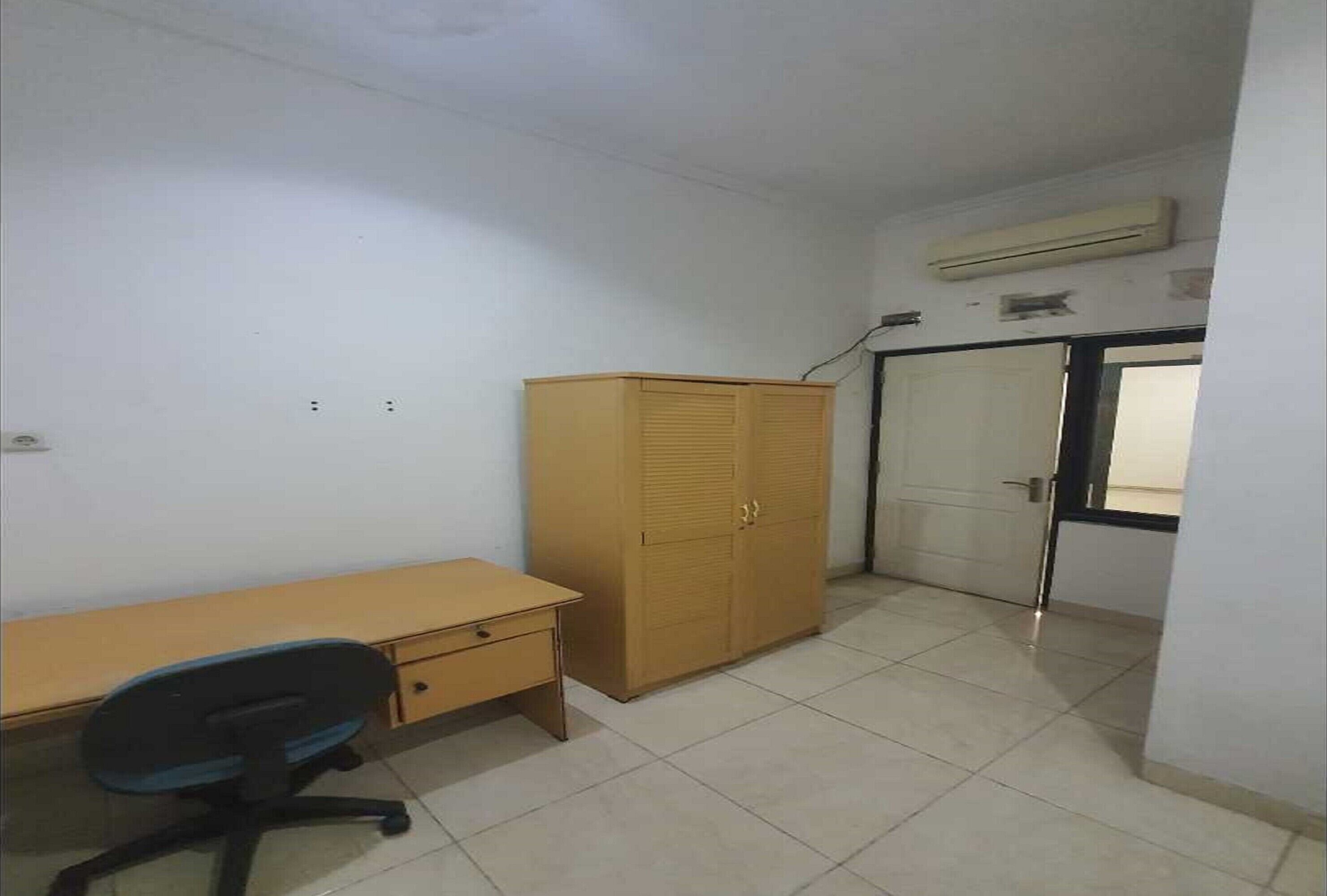 A room with a wooden desk, a chair, a wardrobe, and a door.