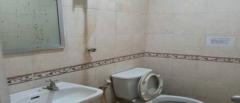 A small bathroom with a sink, toilet, and shower.