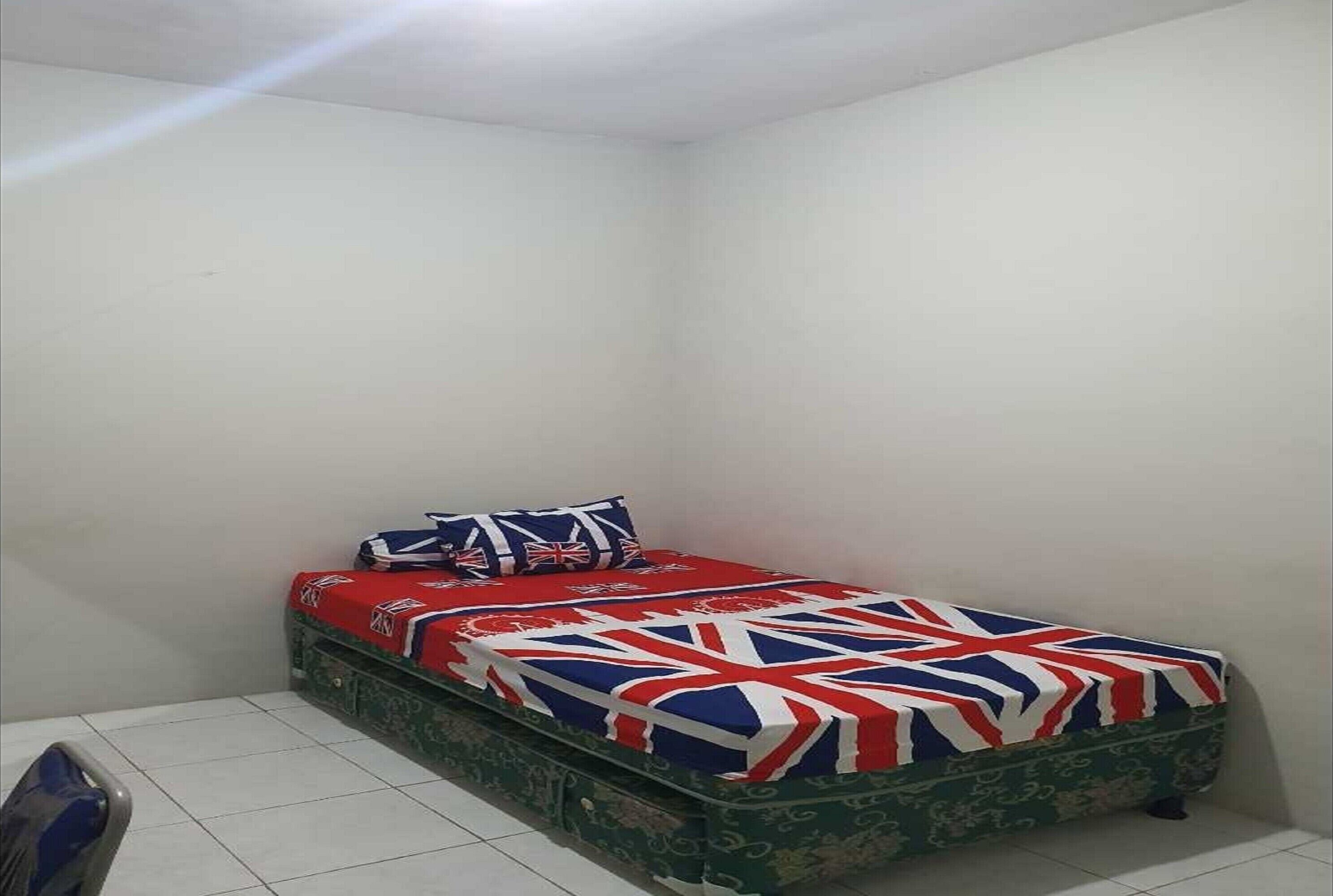 A small, single-bed room with a patterned green mattress and a Union Jack-themed bedspread.