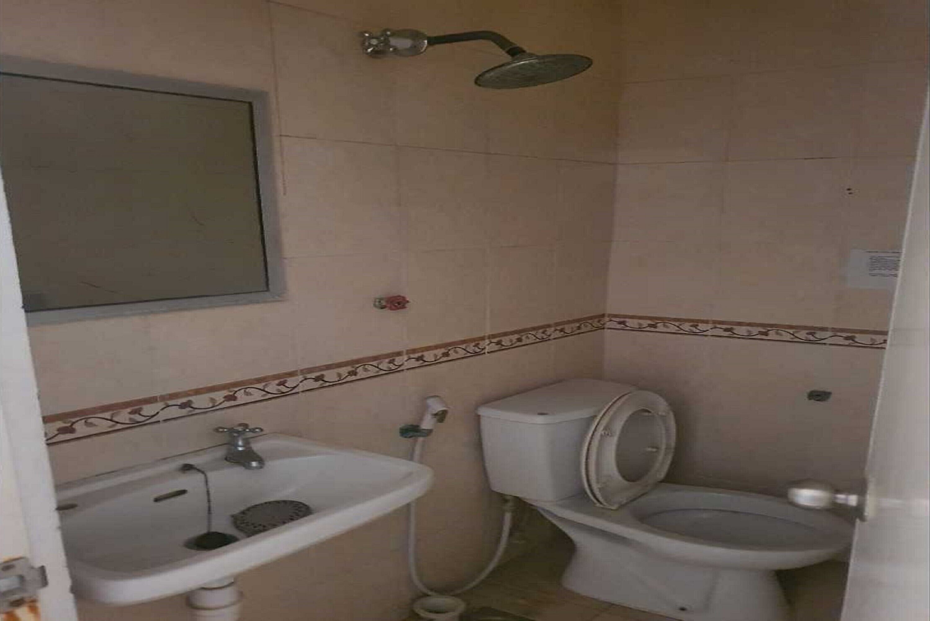 A small bathroom with a toilet, sink, and shower.