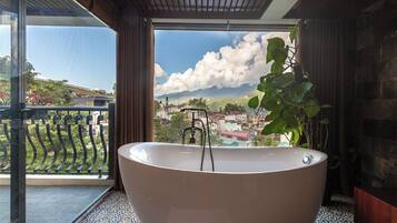 Une grande baignoire sur pieds, placée dans une pièce offrant une vue sur la ville et les montagnes.
