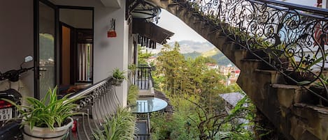A balcony with a view of a mountainous landscape, a potted plant, and a motorcycle.