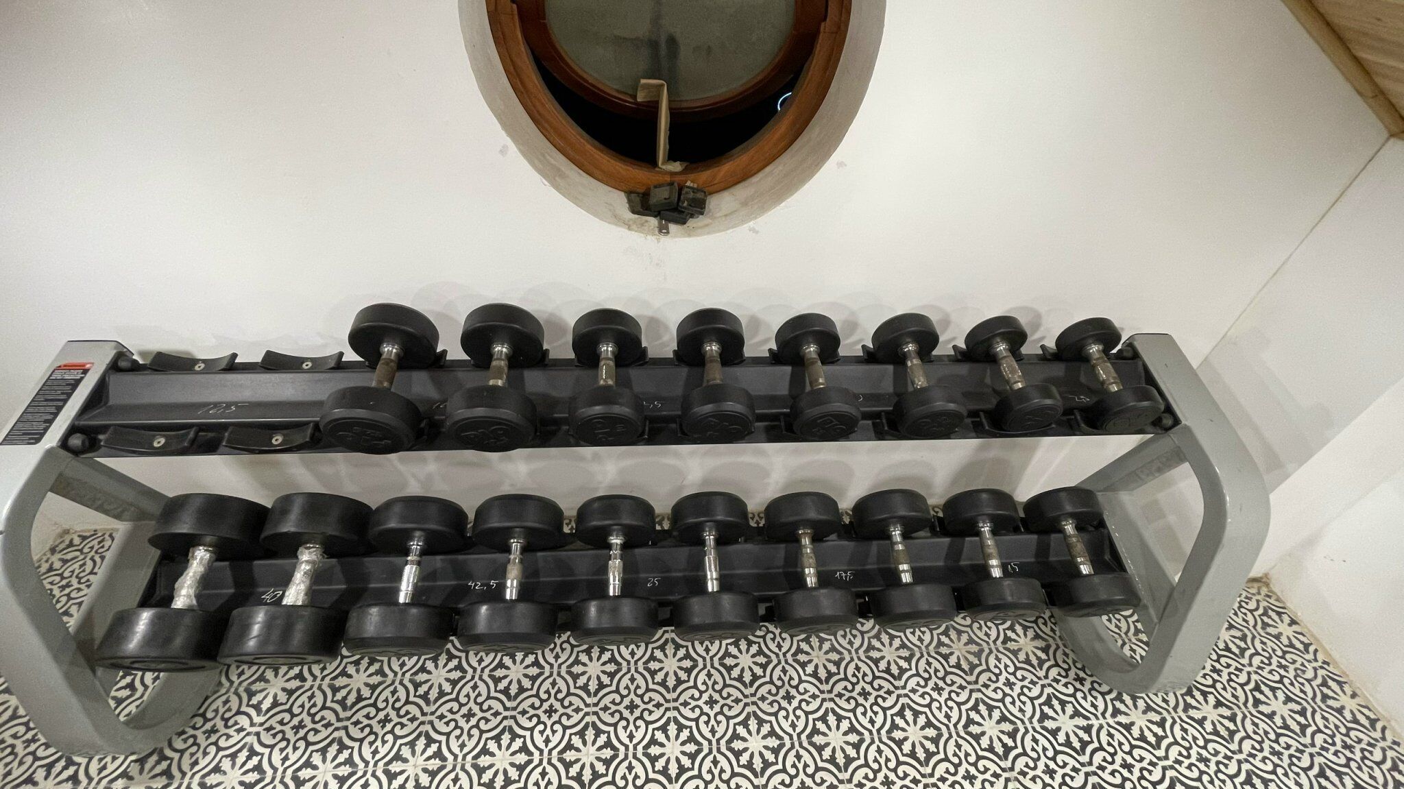 Banco de pesas con varios mancuernas organizadas en filas.