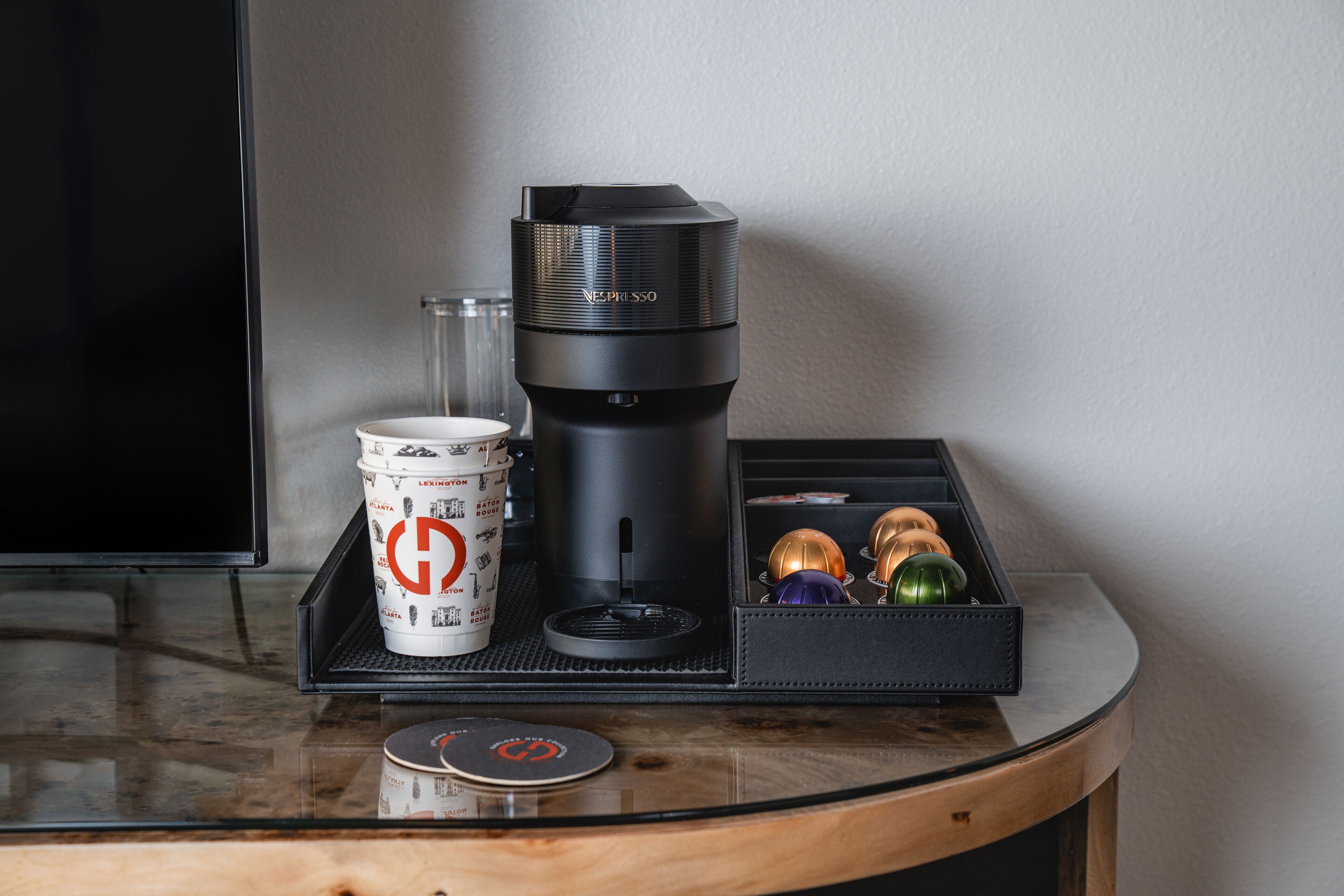 Une machine à café, une tasse et un plateau agrémenté d’objets décoratifs, le tout posé sur une table.