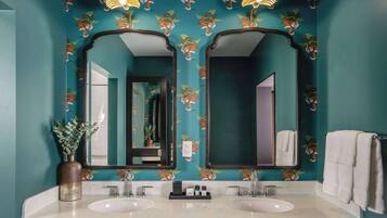 Un baño con paredes verde azulado, dos lavamanos y espejos.