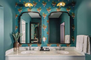 A bathroom with teal walls, two sinks, and mirrors.
