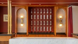 A reception area with a marble counter, a wall of cylindrical objects, and two wall-mounted light fixtures. - Origin Baton Rouge, a Wyndham Hotel (Baton Rouge)