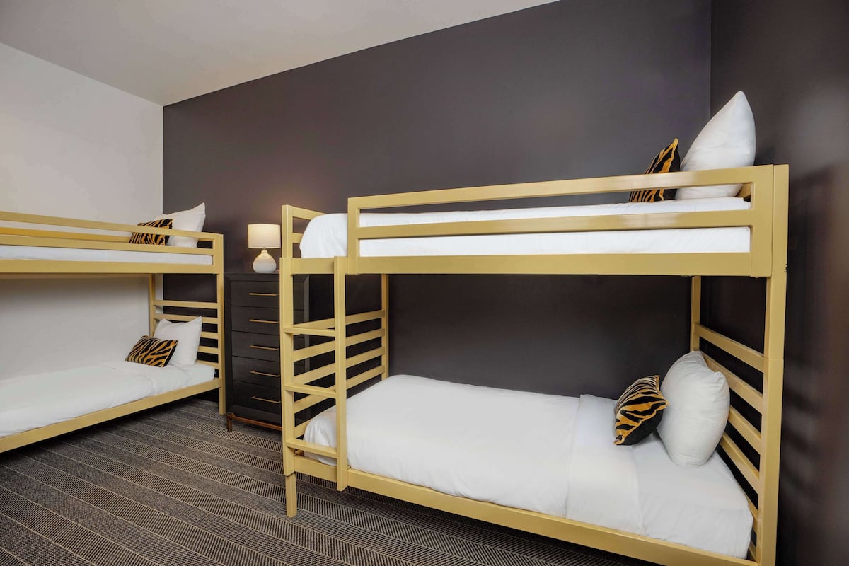 A room with two bunk beds, each with a white mattress and a tiger-patterned pillow.