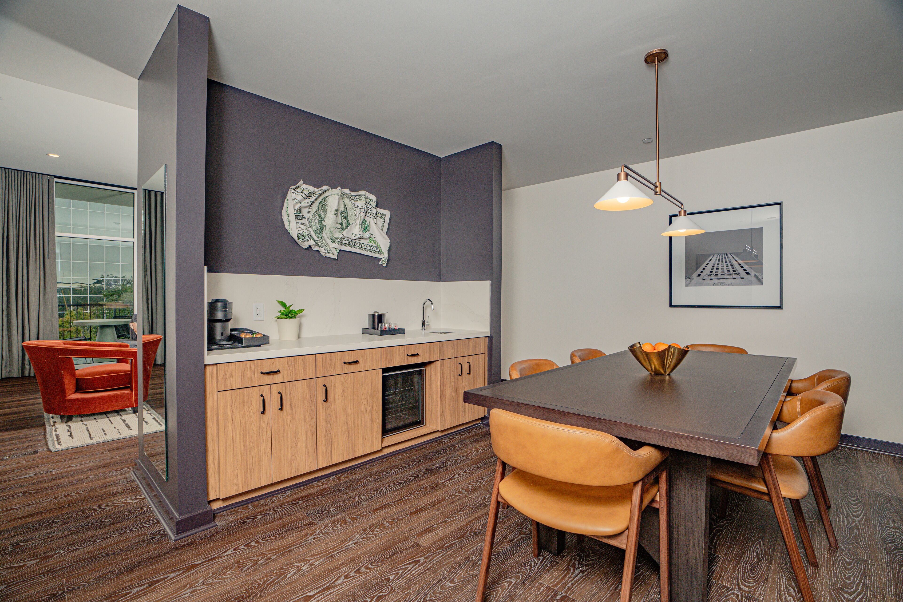 A modern kitchen with wooden cabinets, a dining table with chairs, and a pendant light.