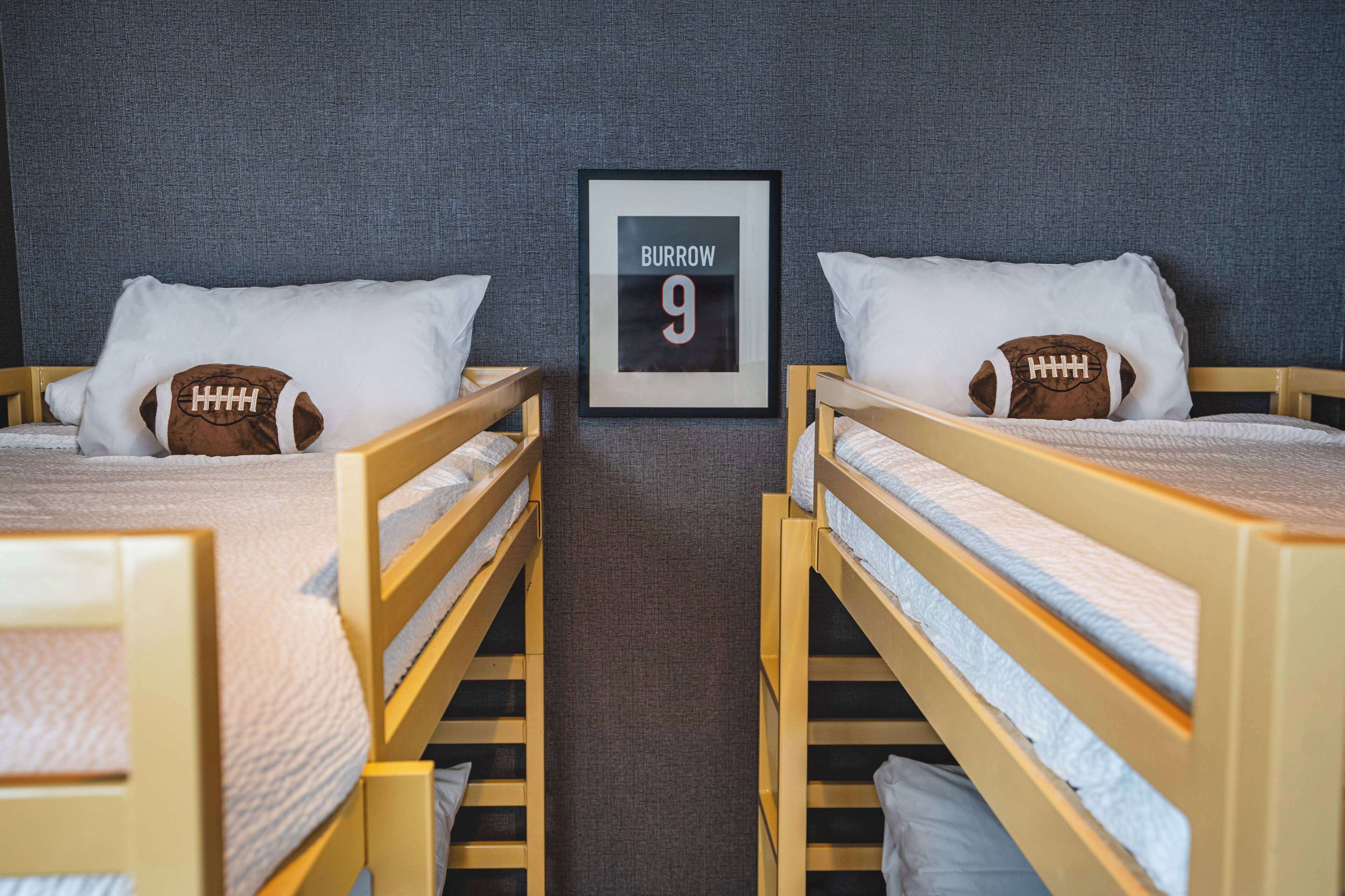 Two bunk beds with football-themed pillows and a framed sign on the wall.
