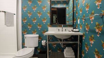 A bathroom with a toilet, sink, and mirror. The walls have a tiger print wallpaper.