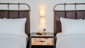 A double bed with a nightstand in between, a wall-mounted light, and a small plant on the nightstand. - Origin Baton Rouge, a Wyndham Hotel (Baton Rouge)