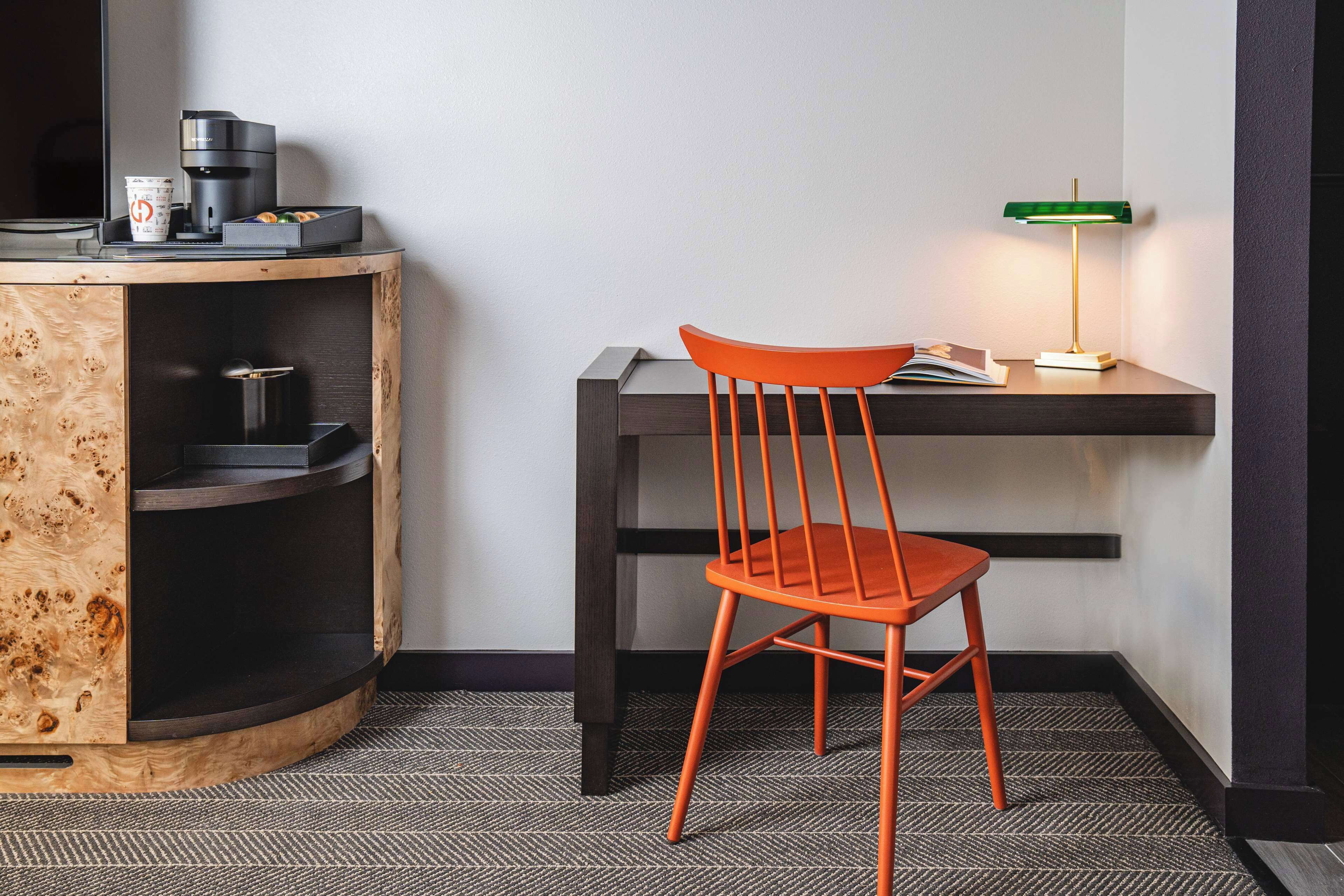 A compact workspace with a wooden cabinet, a chair, a desk, and a lamp.