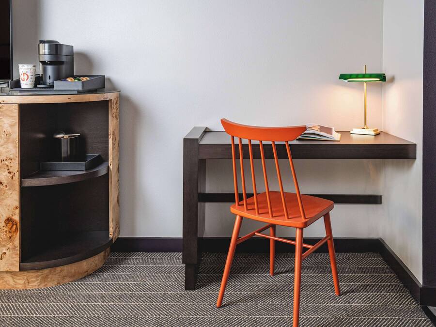 A compact workspace with a wooden cabinet, a chair, a desk, and a lamp.