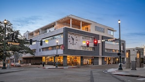 A modern hotel with a prominent clock facade, multiple floors, and a balcony on the upper level. - Origin Baton Rouge, a Wyndham Hotel (Baton Rouge)